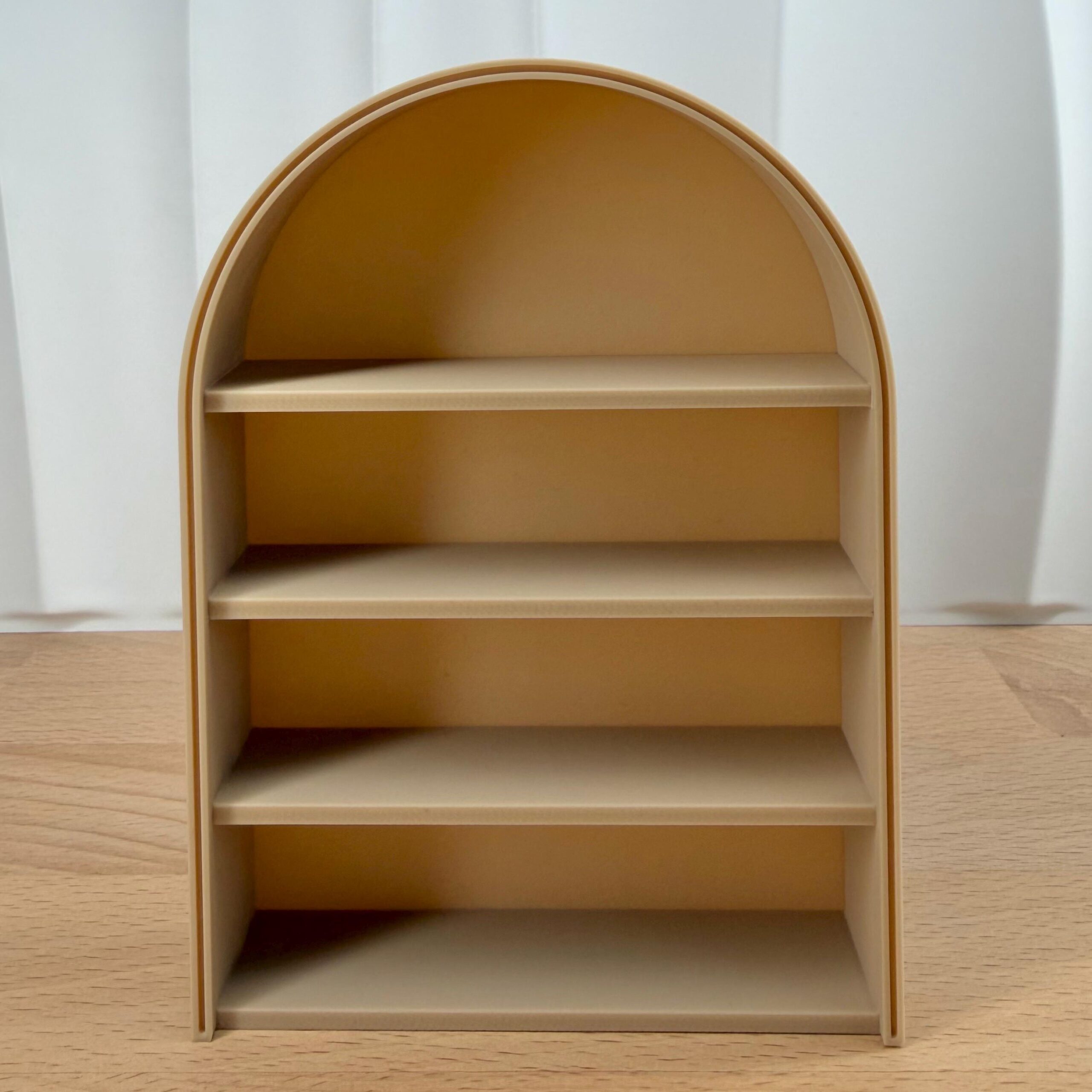 Empty 3D print 1:12 scale arched anxiety bookshelf in beige on a wooden table. Support-free STL file model for miniature dollhouse furniture.